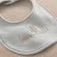 Light blue baby bib with embroidered teddy and "Born in 2027" text
