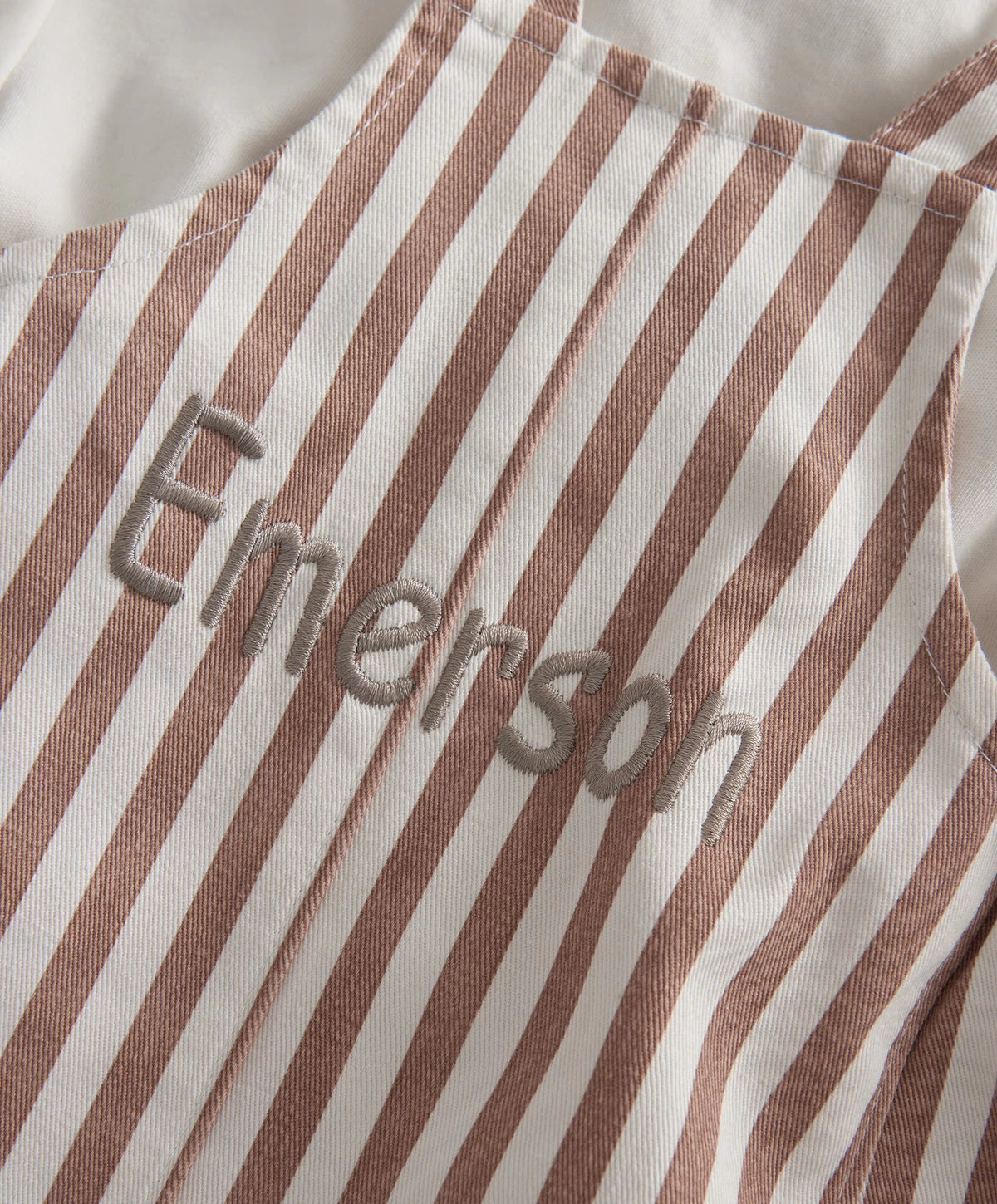 Close-up of brown-and-cream vertical stripe fabric with stitched script detail