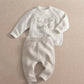Cream knit 2-piece baby set with long-sleeve top and pants, 'hello world' embroidery, ribbed cuffs.