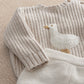 Cream sweater detail with duck applique patch and ribbed knit cuffs