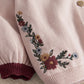 Light pink knit sleeve with floral embroidery and maroon ribbed cuff