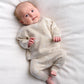 Baby wearing cream duck-knit 2-piece set: long-sleeve top and matching pants with speckles.