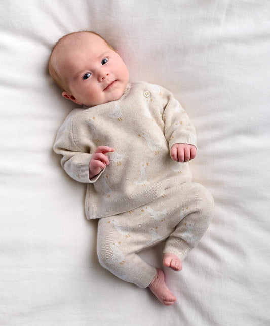 Baby wearing cream duck-knit 2-piece set: long-sleeve top and matching pants with speckles.