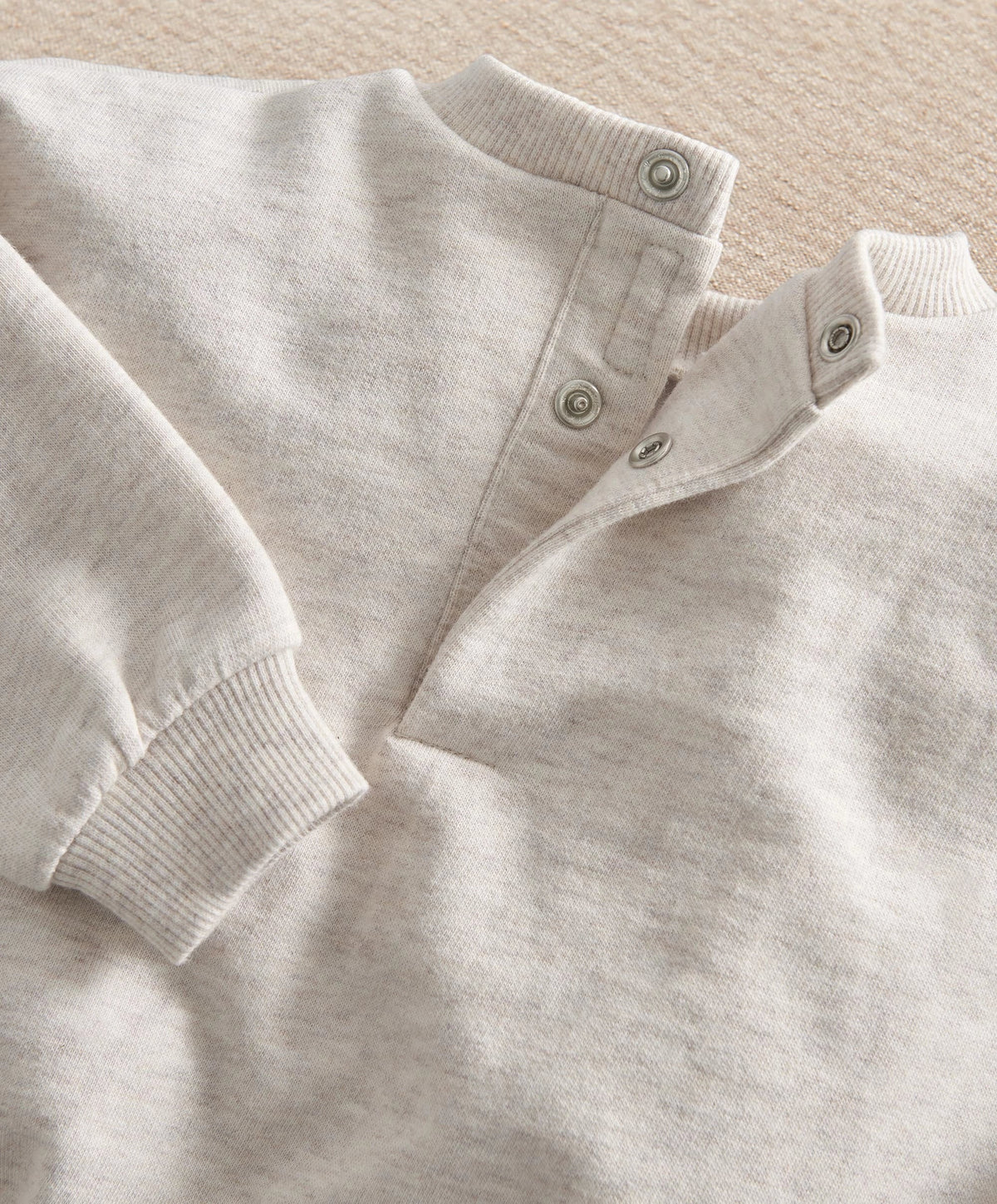 Light gray sweatshirt with ribbed collar and cuff, snap-button placket detail