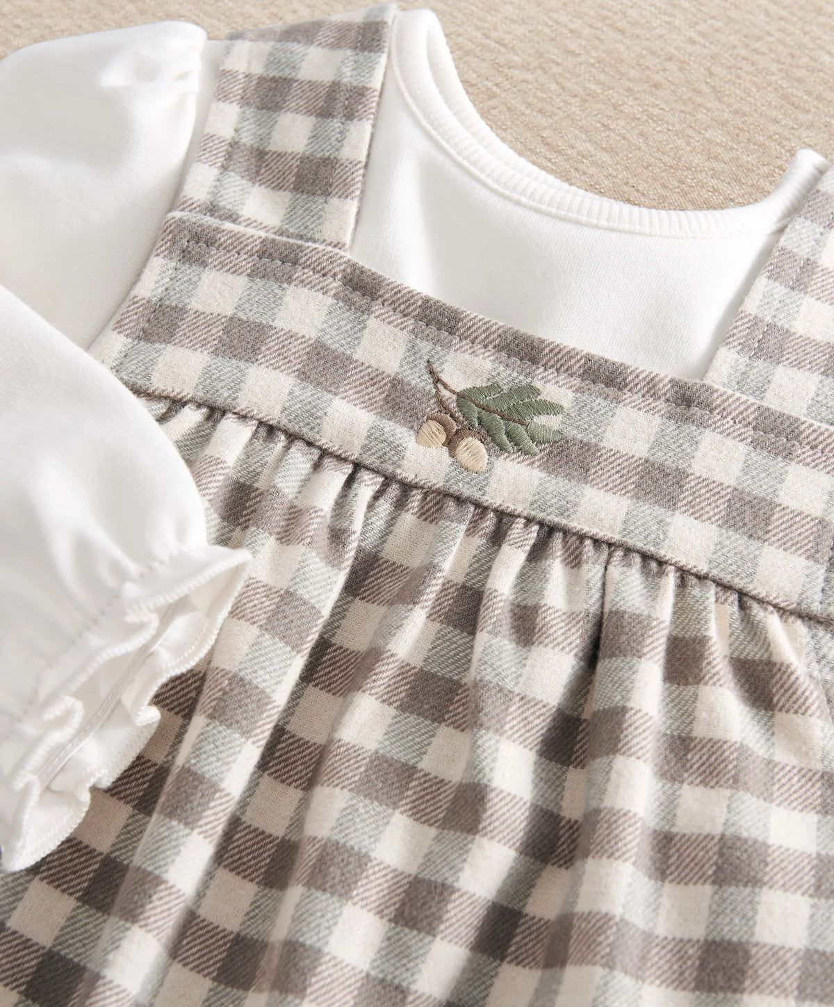 Gingham plaid dress bodice with gathered ruffle yoke over white long-sleeve bodysuit