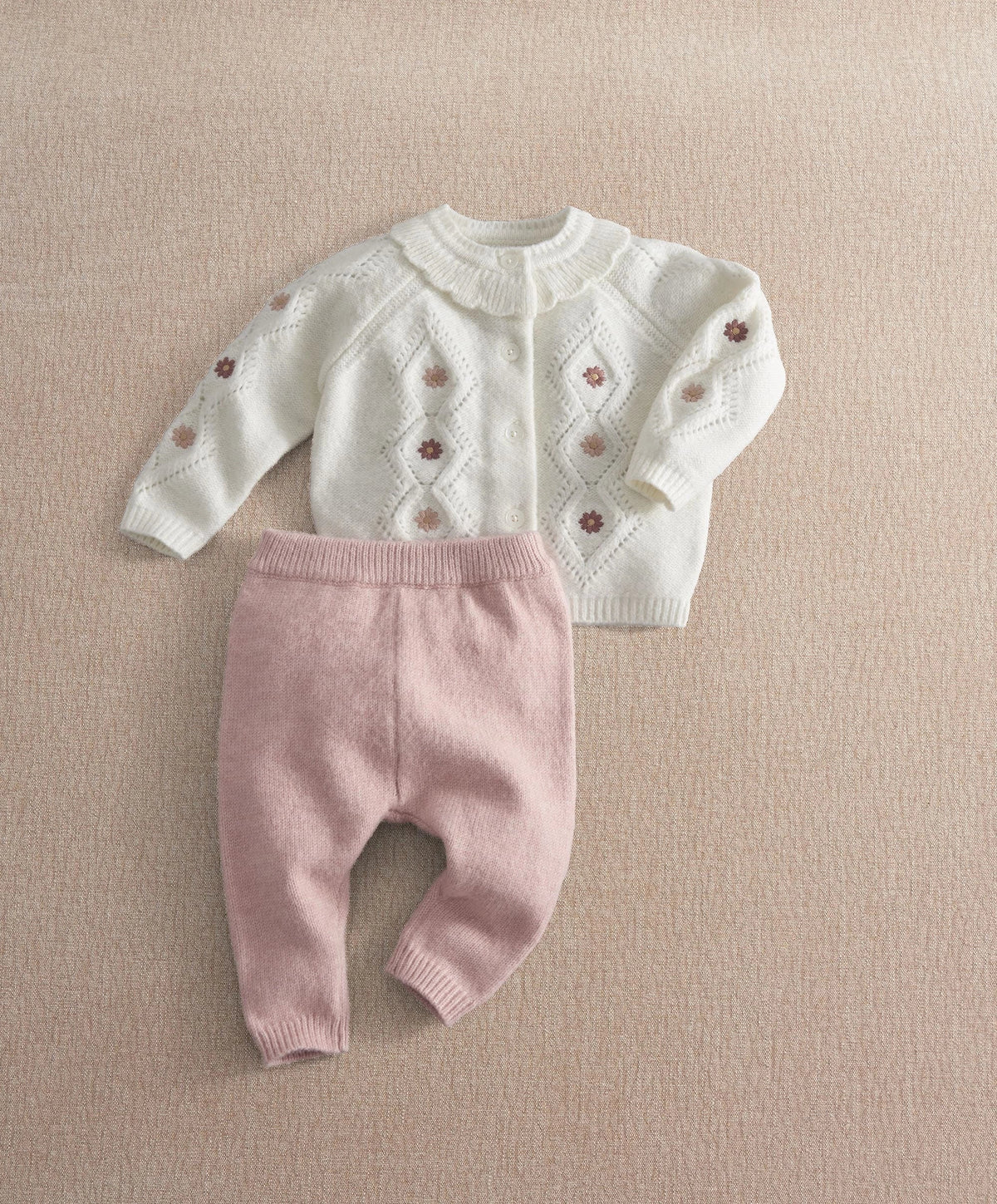Cream embroidered knit cardigan with button front and mauve knit leggings, flat lay.