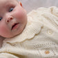 Cream knit cardigan close-up with textured stitch, floral embroidery, and button placket.