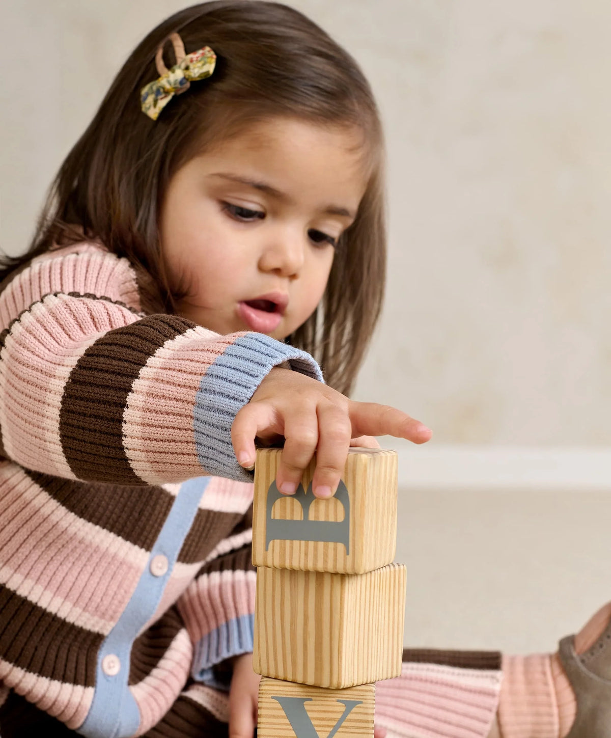 Child wearing striped cardigan and knitted wide-leg trousers set, pink and brown stripes