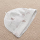 White printed baby hat with whimsical animal motifs
