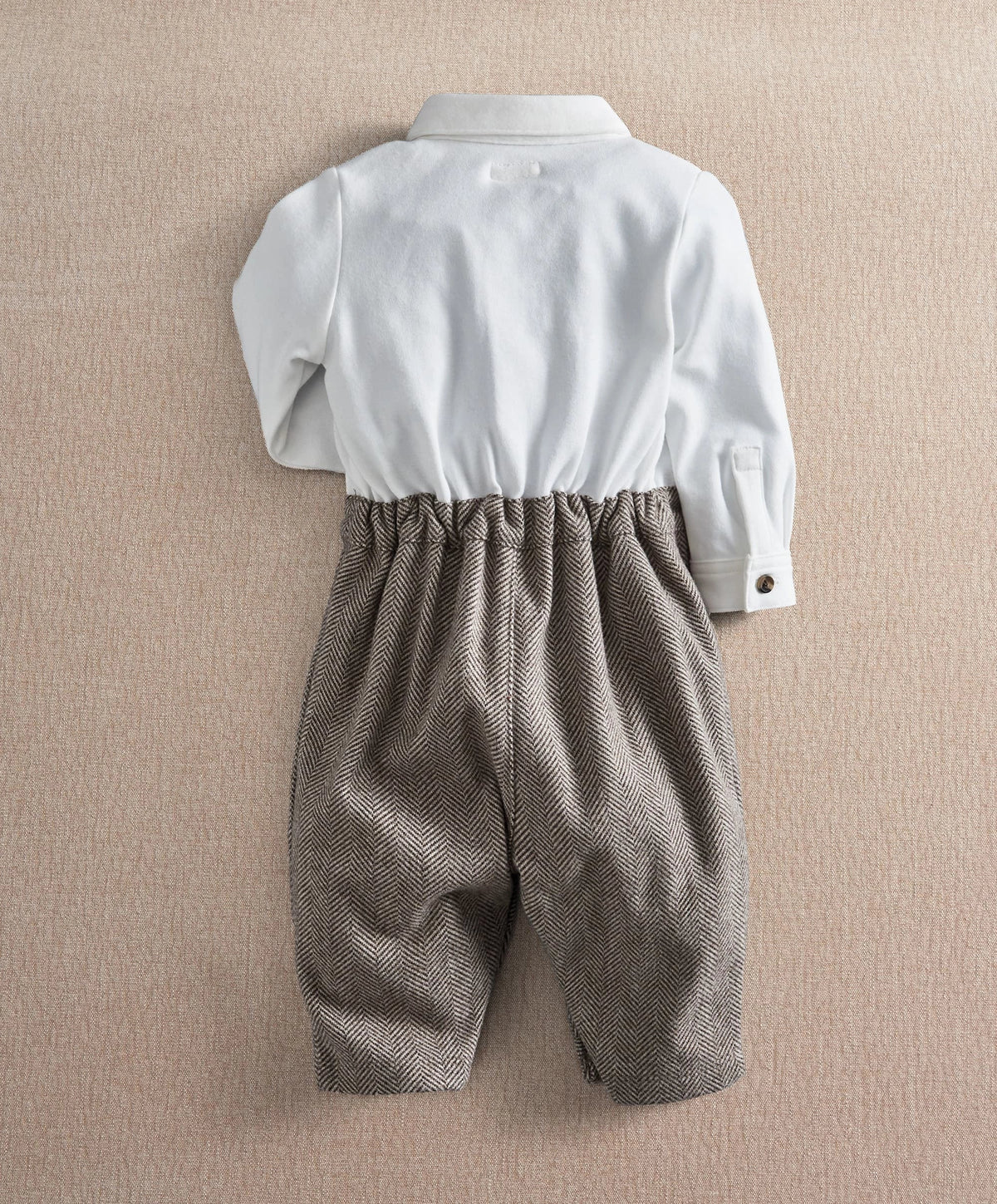 Back view of white-and-dark herringbone romper with buttoned back and gathered waist