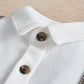 White mock-neck romper detail with brown and black buttons on collar placket