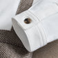 White mock-neck romper cuff with buttoned placket and dark herringbone panel