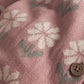 Pink knitted romper fabric with white floral print and round wooden button