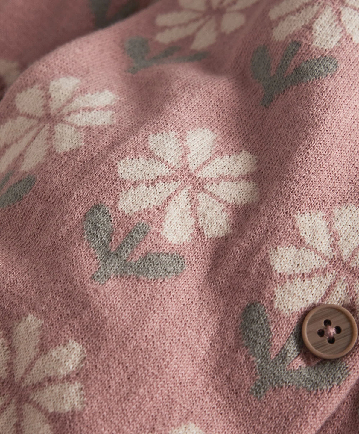 Pink knitted romper fabric with white floral print and round wooden button