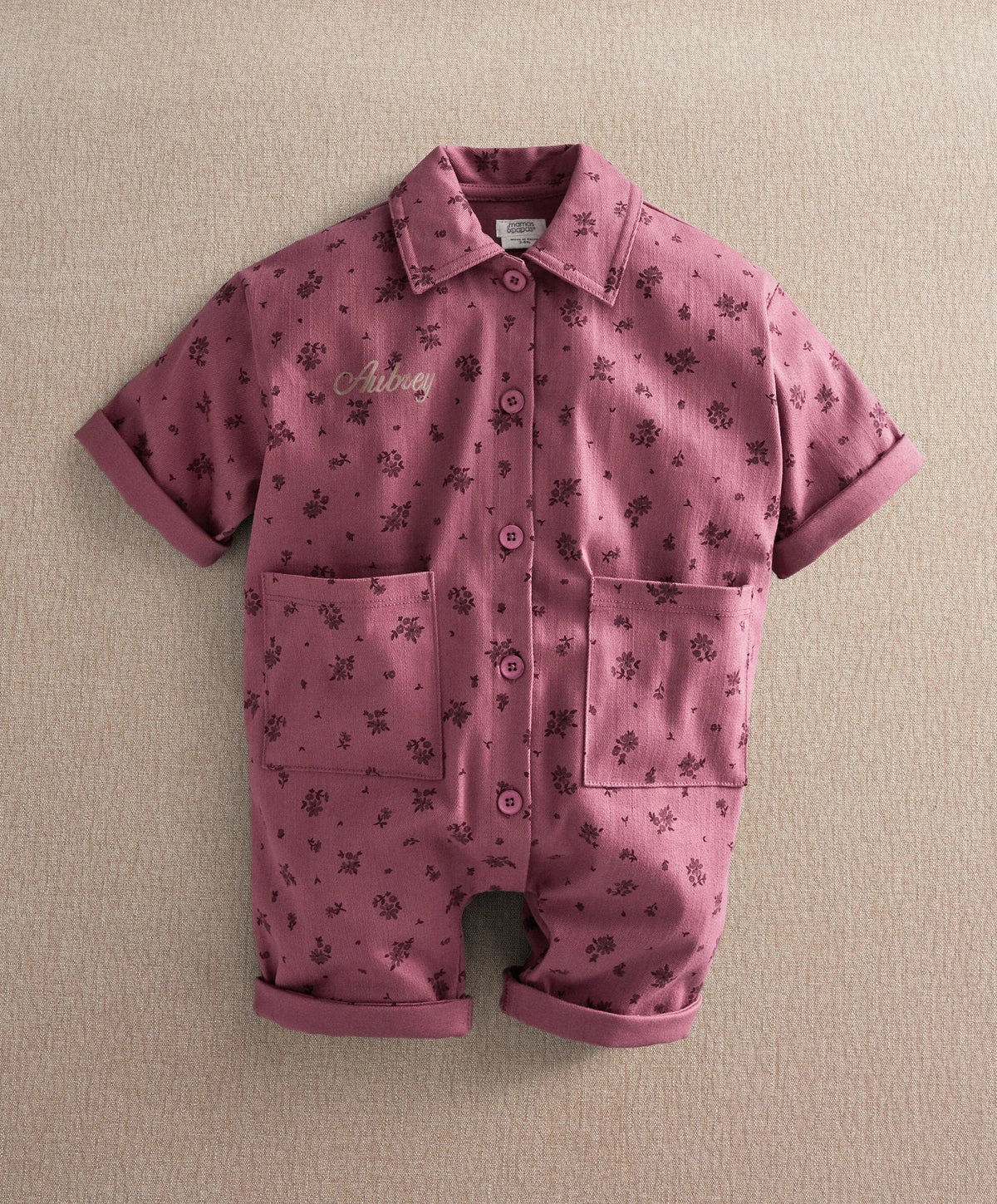 Purple floral short-sleeve romper with button front and two chest patch pockets