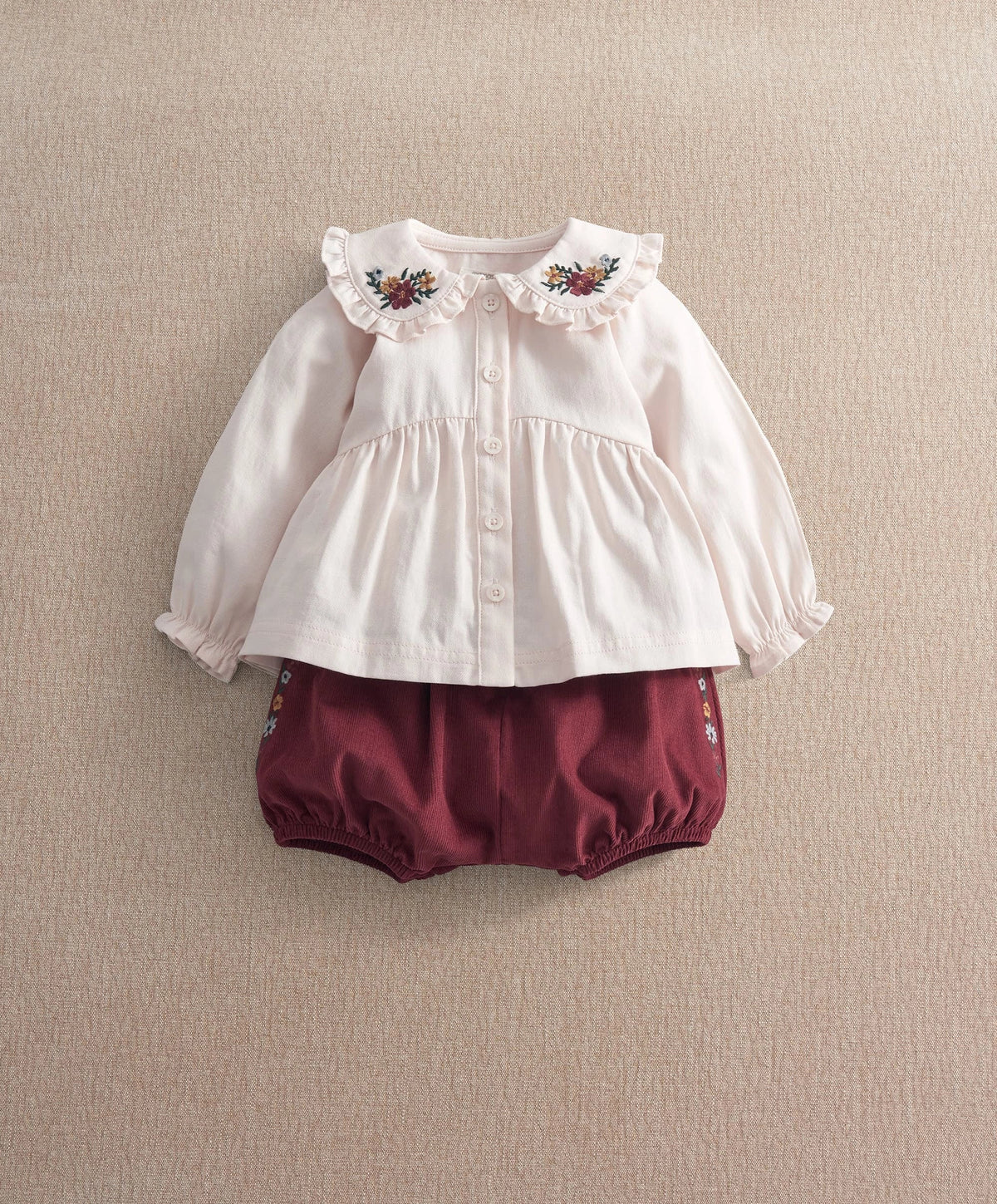 White long-sleeve top with floral embroidered collar, button front, ruffle cuffs.