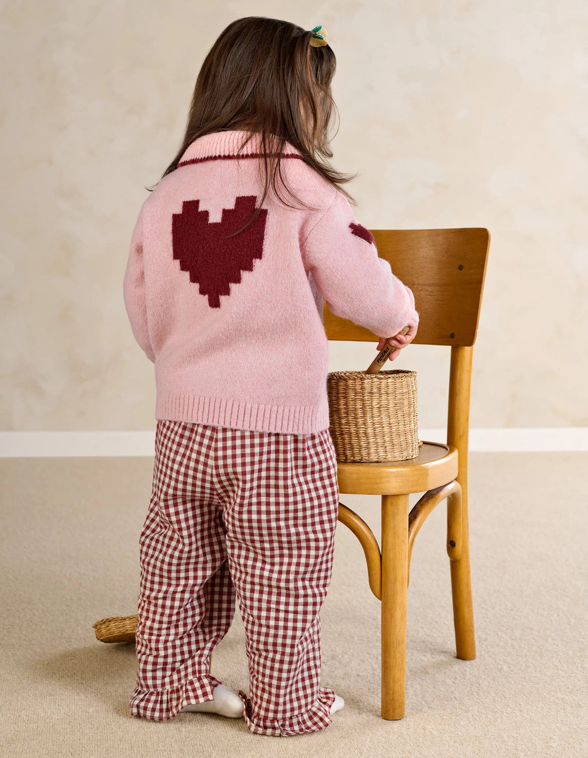 Pink knit heart cardigan with dark red heart intarsia and button placket, back view