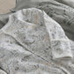 Close-up of baby sleepsuit with light dino print and ribbed cuffs