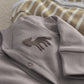 Gray baby sleepsuit with small horse applique on chest and ribbed footed cuffs.