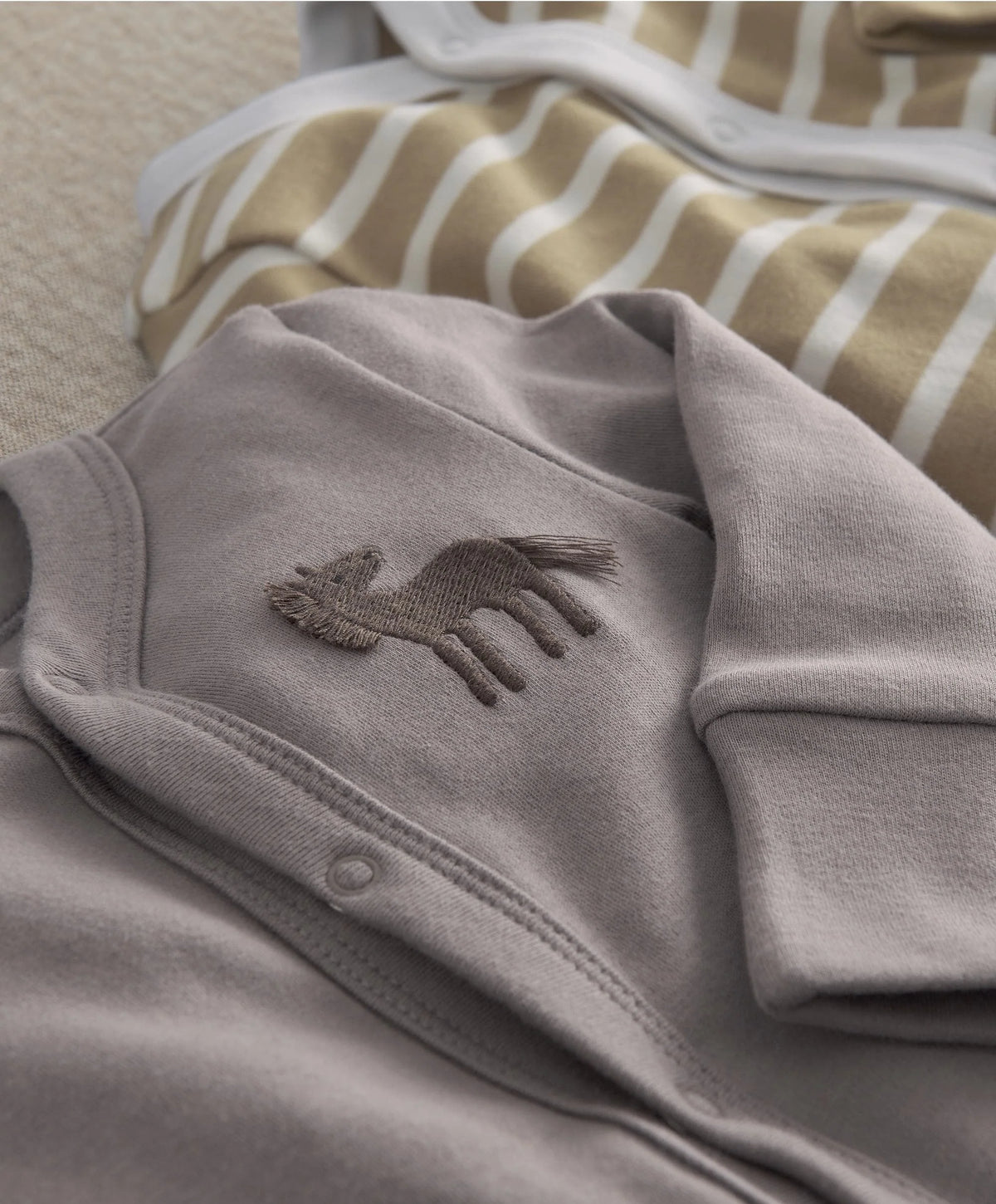 Gray baby sleepsuit with small horse applique on chest and ribbed footed cuffs.