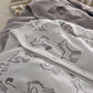 White baby sleepsuit with dark horse icon print and snap button at leg opening.