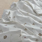 White sleepsuit with small gold symbol print and snap-button leg openings