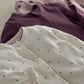 Cream baby sleepsuit with small dotted print and ruffled cuffs; plum zip