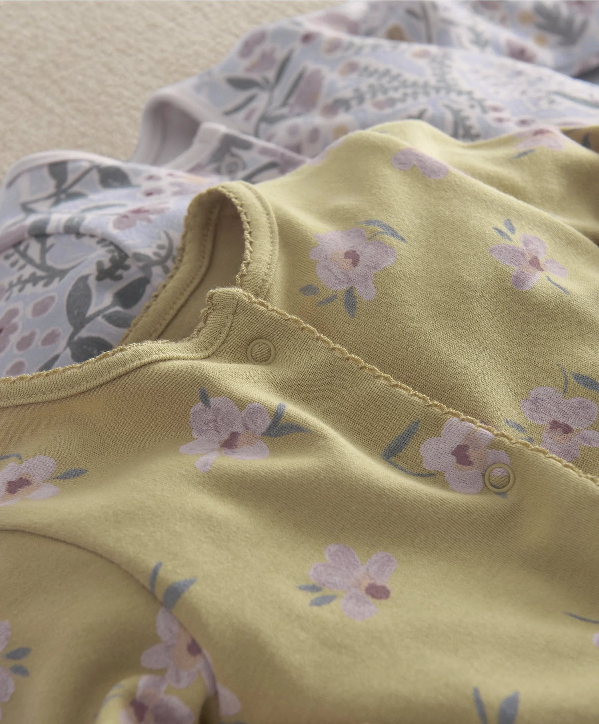 Yellow floral baby romper with snap placket and gathered neckline detail