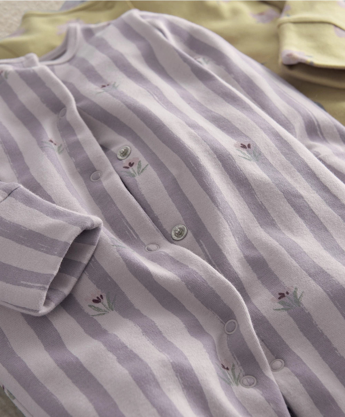 Lavender striped baby romper close-up with button placket and small floral print
