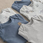 Baby safari bodysuits close-up: blue solid, white animal print, and white striped bodysuits