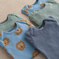 Pack of 5 lion-print bodysuits, overlapping close-up: light blue, mint, navy