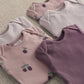 Baby bodysuit set close-up: ribbed light pink and plum purple with berry print