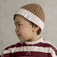 Brown knit beanie with white cuff and BORN WILD label, worn by child
