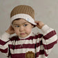Brown knit beanie with white BORN WILD patch, worn by child holding brim