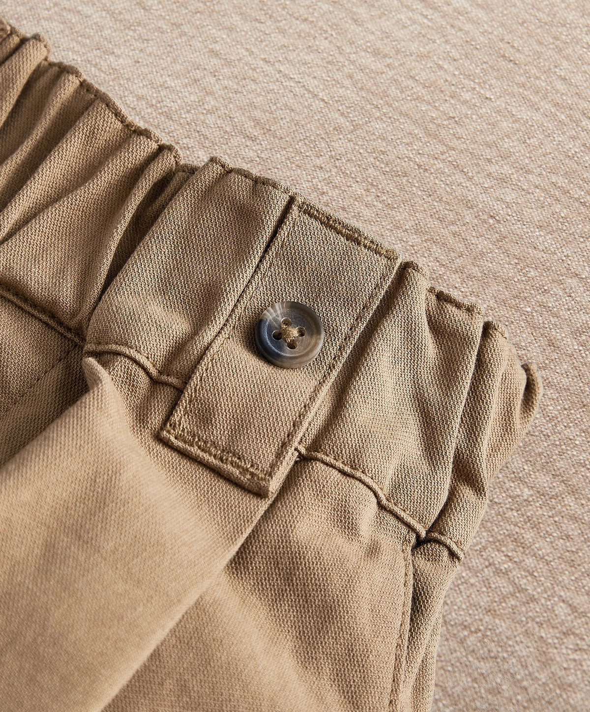 Tan waistband detail with belt loops and button