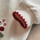 Cream sweatshirt sleeve cuff with red berry embroidery detail and ribbed knit trim