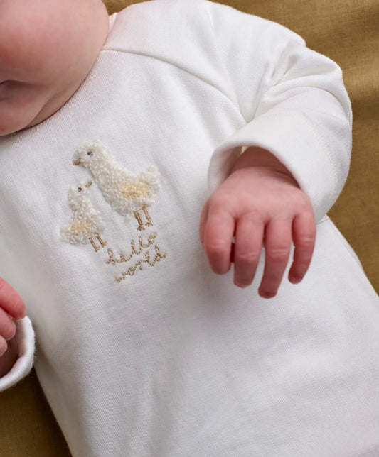 White baby all-in-one with embroidered duck and Hello World text