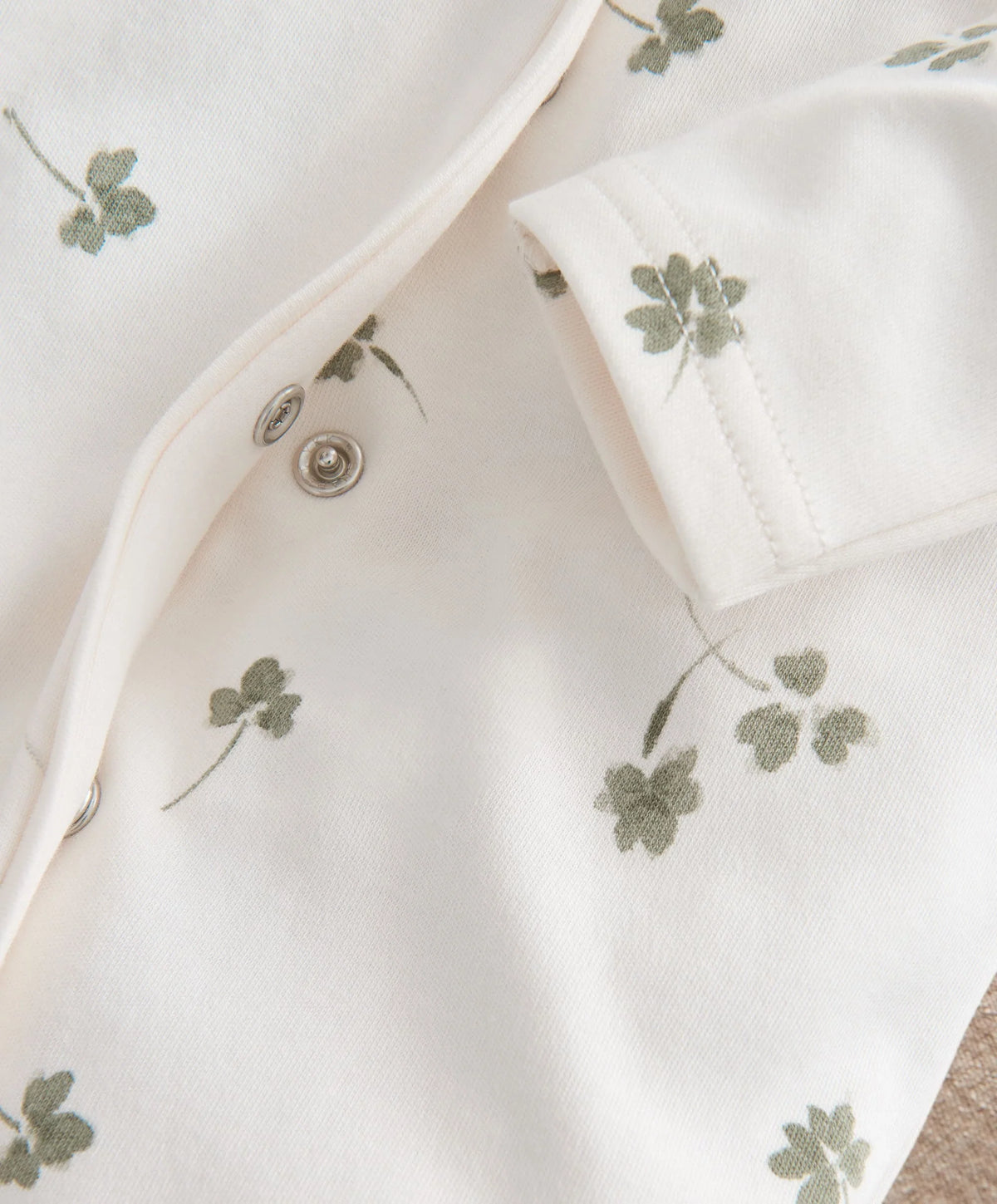 Clover-print baby romper close-up with button placket and long sleeves