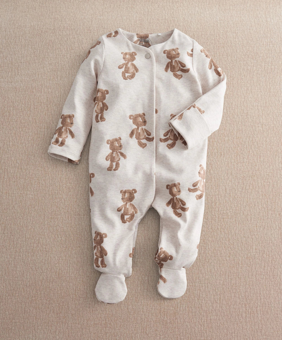White footed all-in-one romper with brown bear print, long sleeves, snap front.