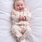 All-in-one baby outfit in off-white with large brown floral print, long sleeves.