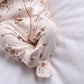 Off-white floral all-in-one detail with footed cuffs and gathered front placket.