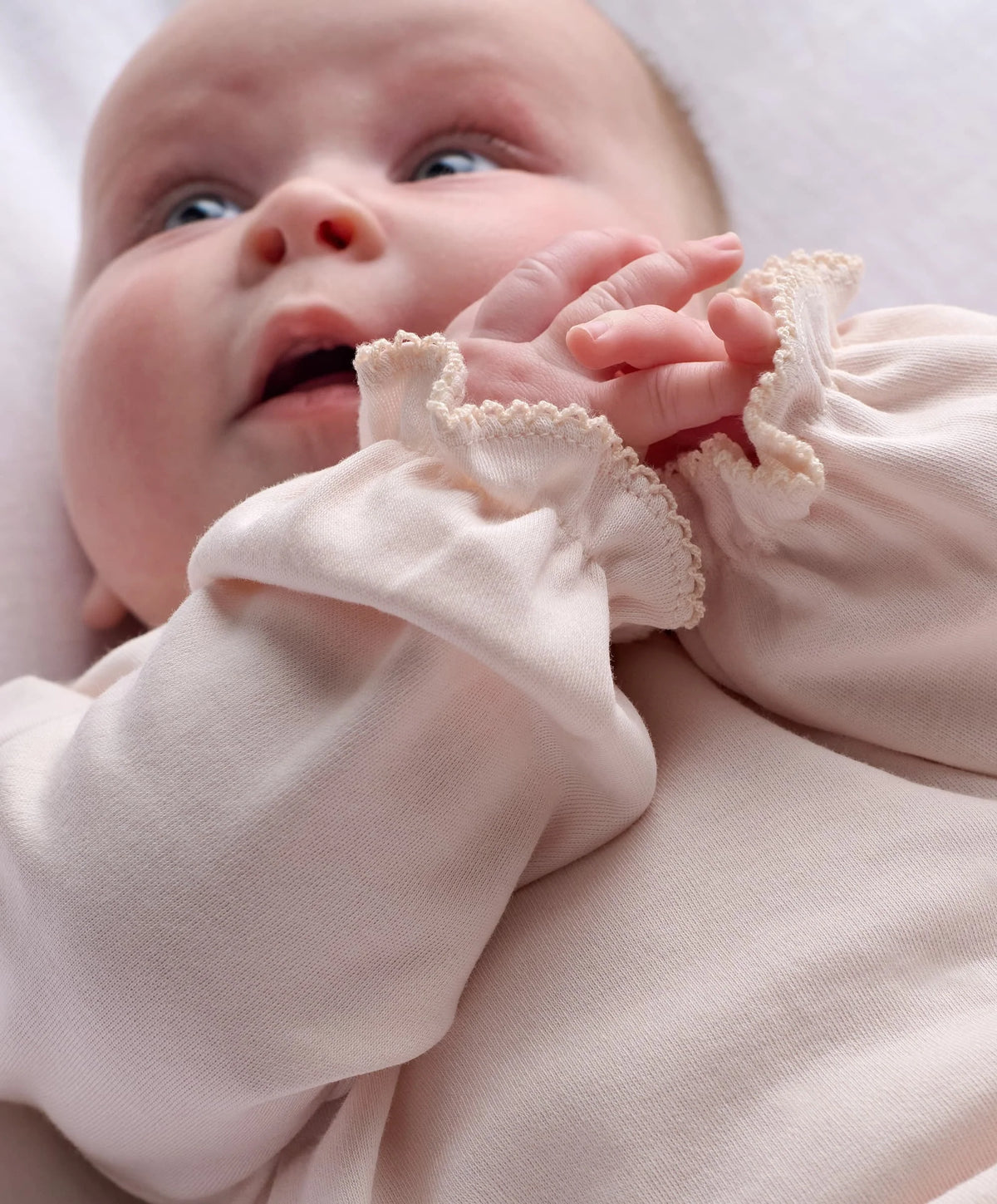 Pink baby onesie with ruffled cuffs and collar