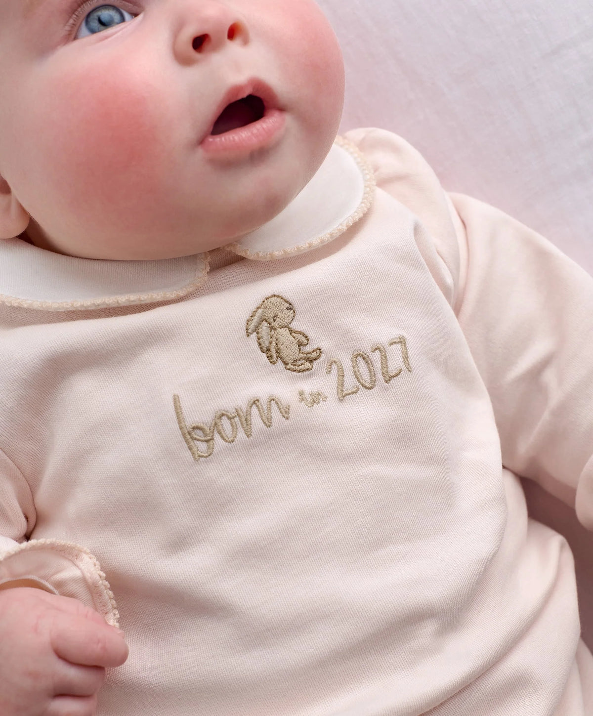 Pink baby onesie with embroidered bear and 'born in 2027' text, long sleeves