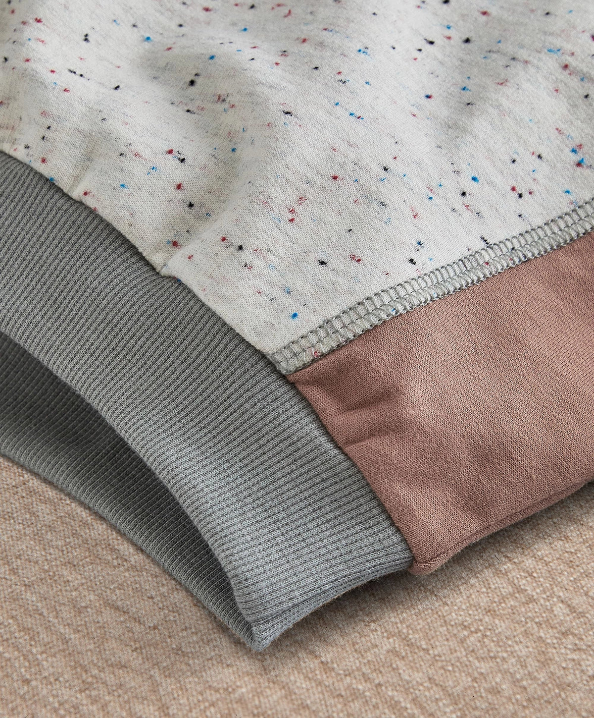 Speckled sweatshirt close-up: gray ribbed cuff and hem with stitched edge