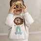 White toddler boucle sweatshirt with lion face applique and teal-striped cuffs