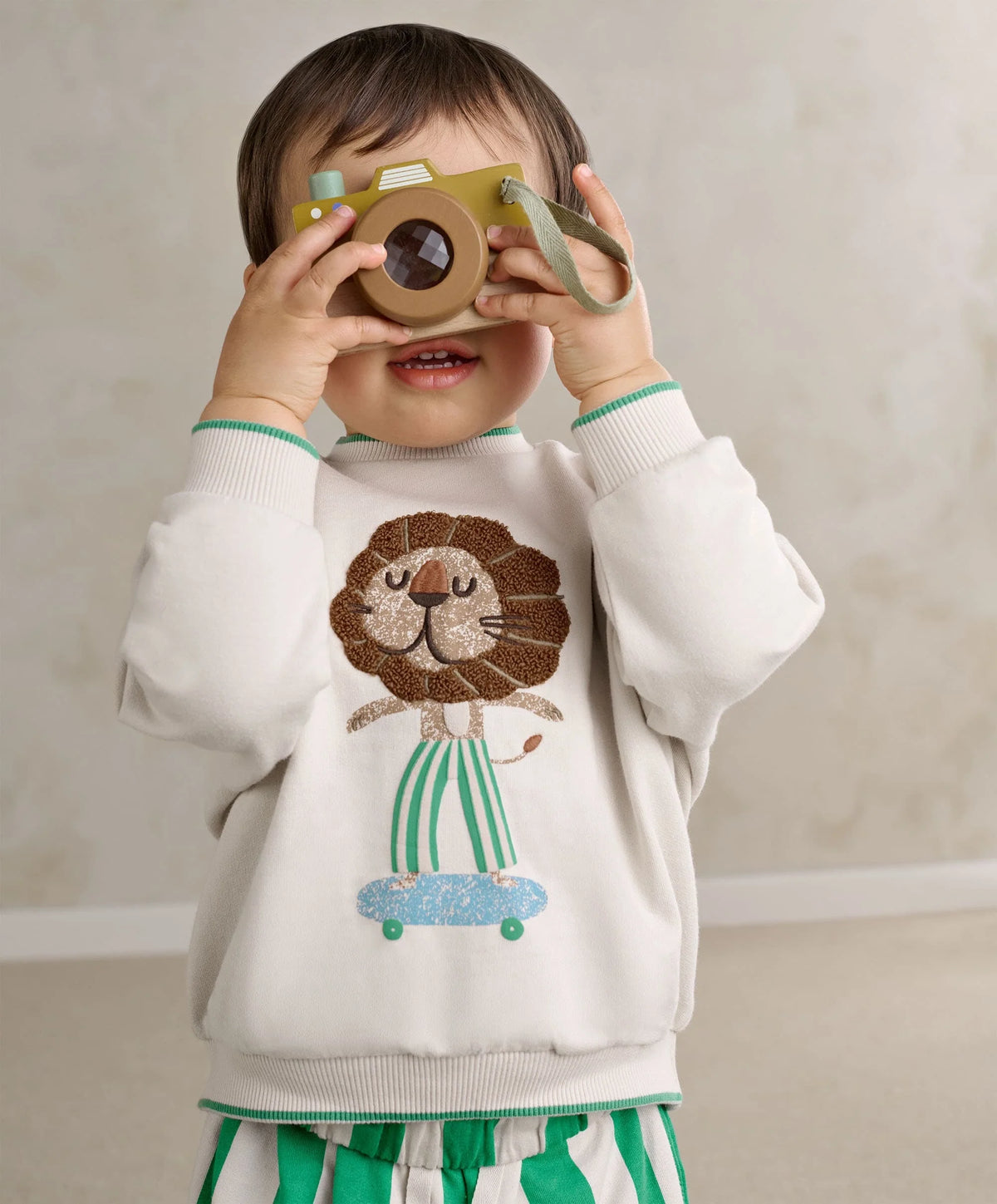 White toddler boucle sweatshirt with lion face applique and teal-striped cuffs