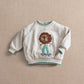 White toddler sweatshirt with lion face applique, teal-trim ribbed cuffs and hem