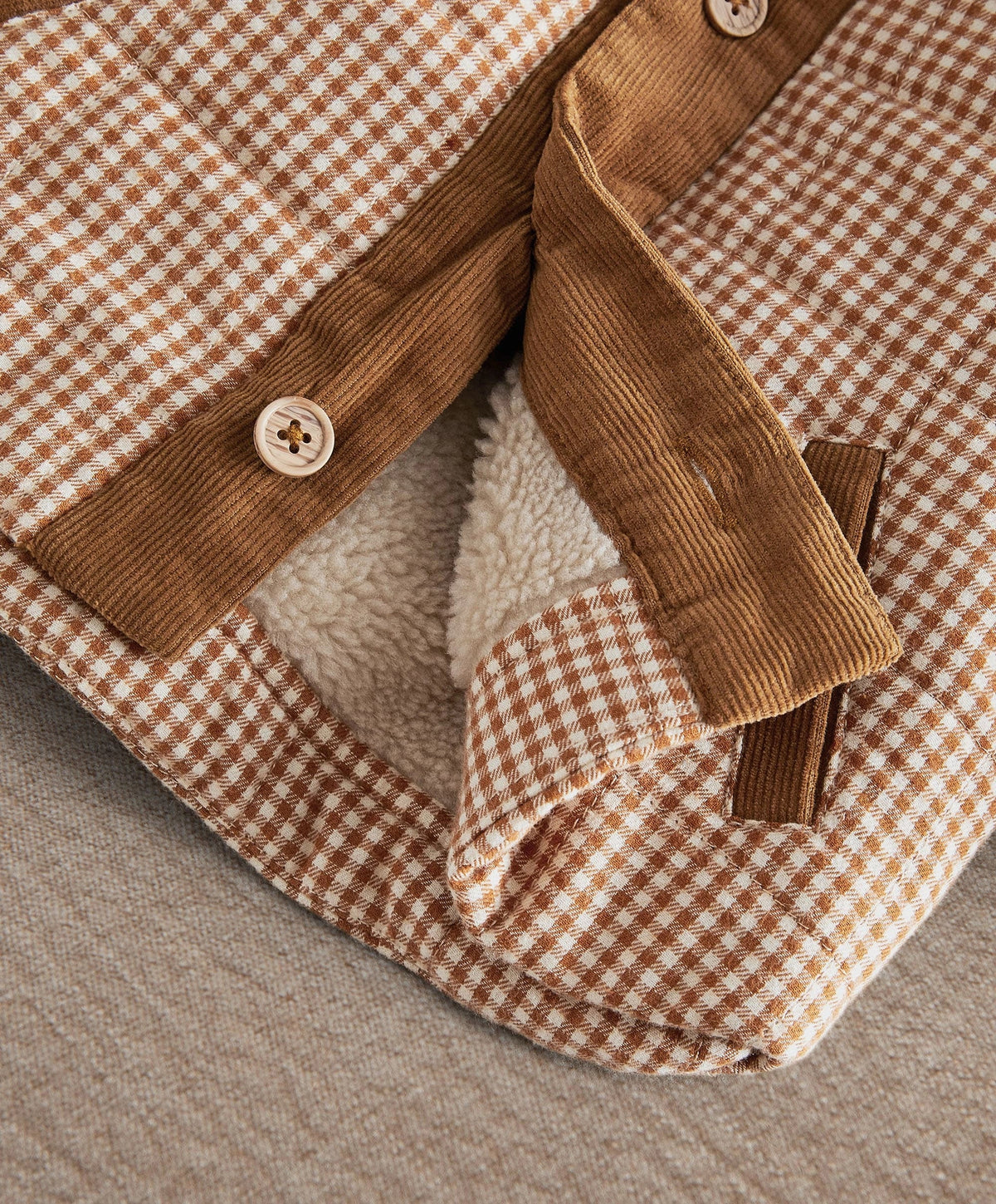 Checked jacket close-up with corduroy sleeves, cozy lining, and snap cuffs