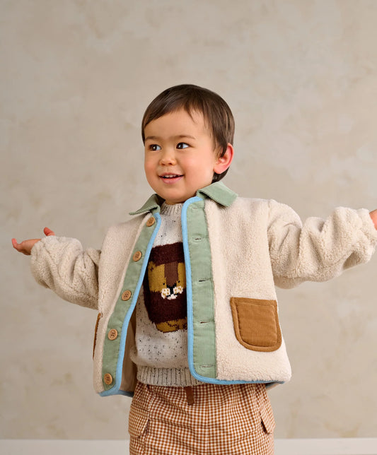 Cream borg jacket with mint lining, blue trim, tan pockets, and wooden button front