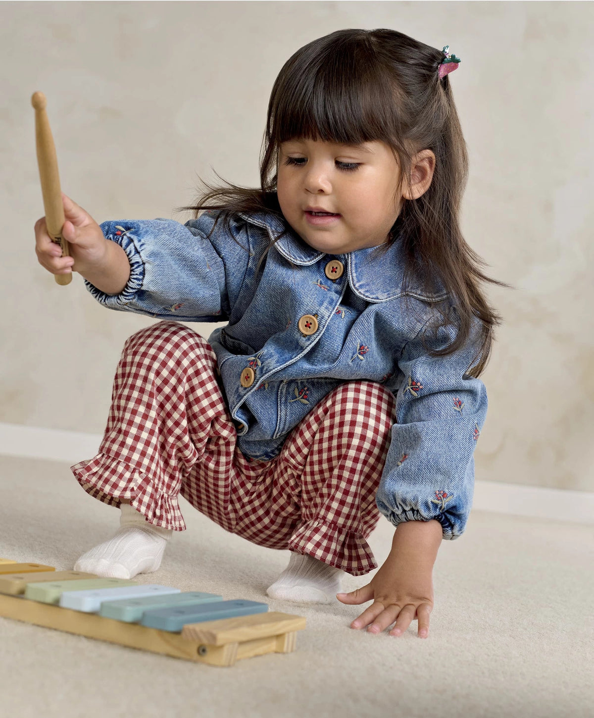Light blue denim jacket with button front and embroidered motifs, child seated